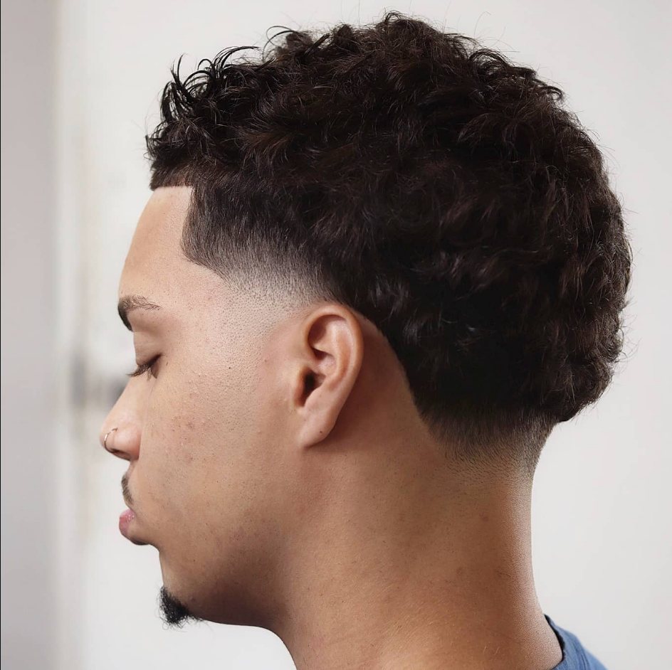 Curly top with a low taper fade and a clean edge-up